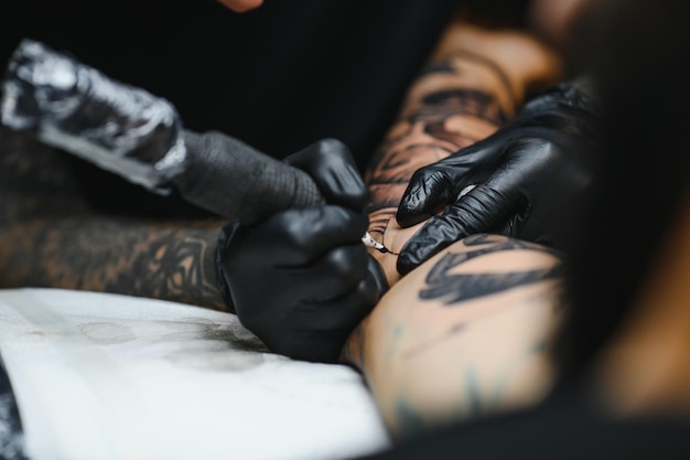 Tatuador com sua máquina tatuando no braço com o desenho desenhado, conceito de arte e design