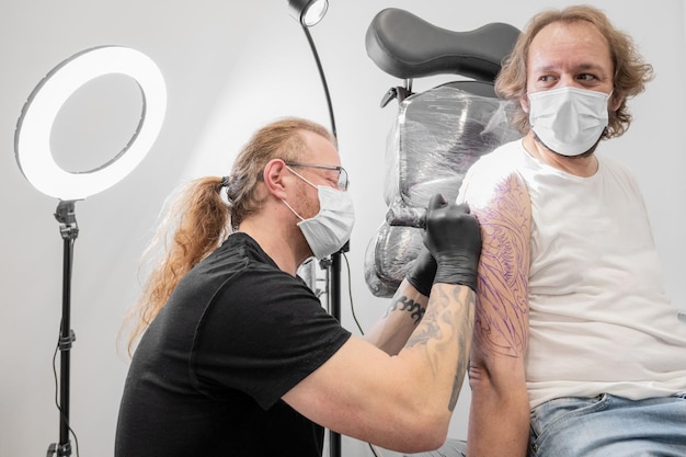Tatuador fazendo tatuagem no estúdio
