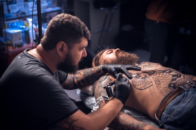 El tatuador hace fotos de tatuajes en el estudio de tatuajes./Maestro del arte de tatuar haciendo fotos de tatuajes en el salón.