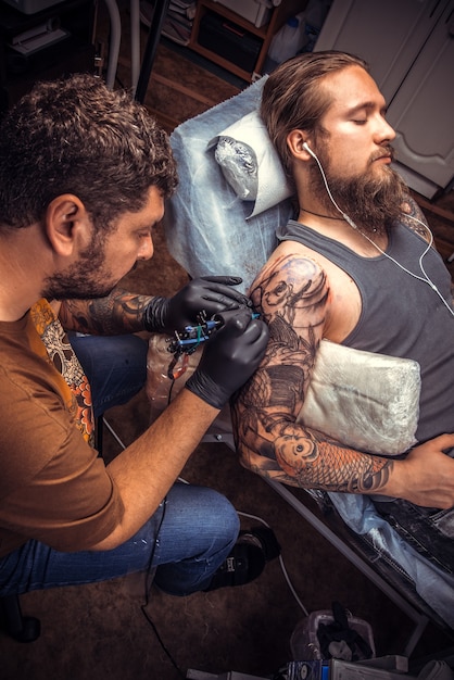 Tatuador hace imágenes de tatuajes en el salón de tatuajes.