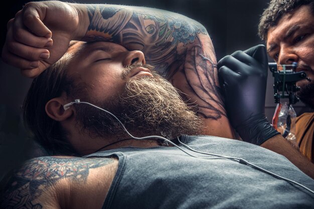 Tatuador haciendo un tatuaje en un salón de tatuajes./Tatuador profesional hace tatuajes en un estudio de tatuajes.