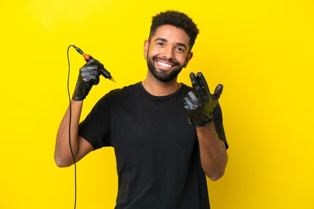 Tatuador homem brasileiro isolado em fundo amarelo convidando para vir com a mão feliz que você veio