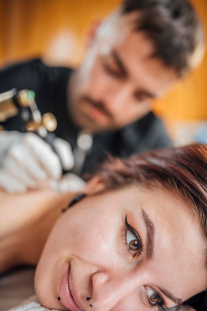 Tatuador masculino tatuando as costas da mulher no estúdio de tatuagem