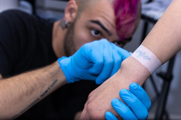 Tatuador poniendo cinta protectora antes de tatuar
