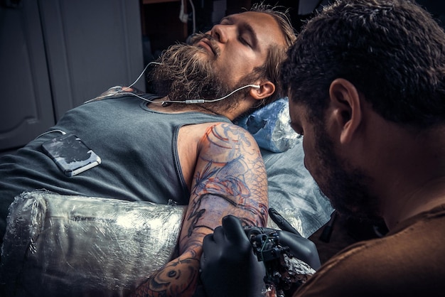 Tatuador profesional crea un tatuaje en un estudio de tatuajes Tatuador profesional en el trabajo en un salón de tatuajes