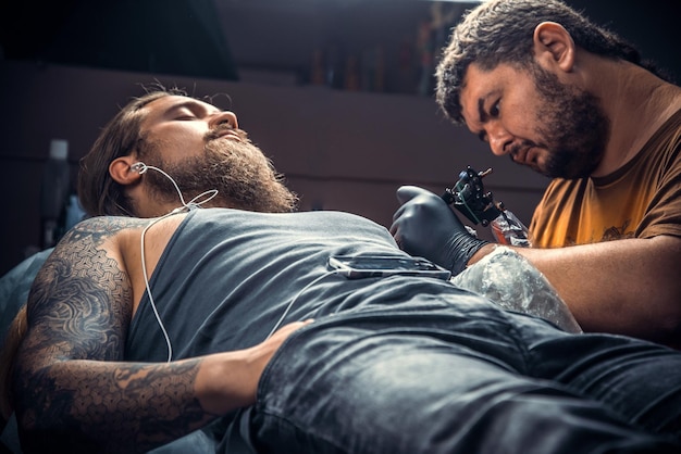 Tatuador profesional crea tatuajes en un salón de tatuajes./Tatuador profesional en el trabajo en un estudio de tatuajes.