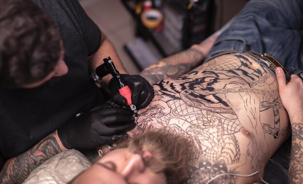 Tatuador profesional hace un tatuaje en el estudio.