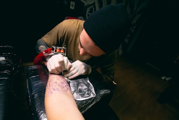 Foto tatuador profesional hace un tatuaje en el primer plano de la mano del cliente