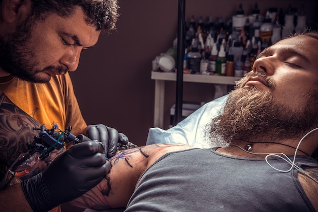Tatuador profesional haciendo un tatuaje en un estudio de tatuajes./Hombre usando guantes en el trabajo en el estudio.