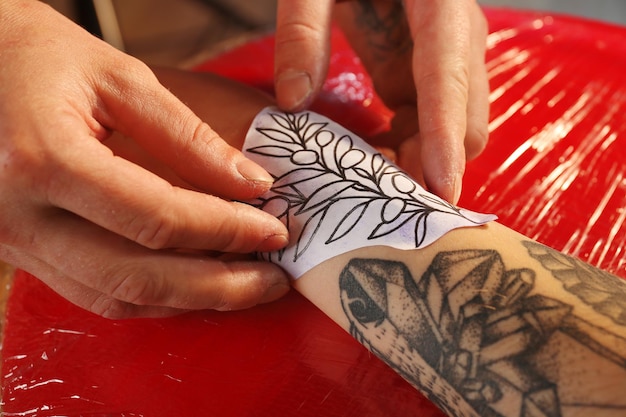 Tatuador profesional haciendo tatuajes en la mano del cliente
