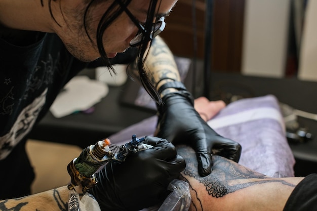 Tatuador profesional mete un tatuaje en la mano del hombre