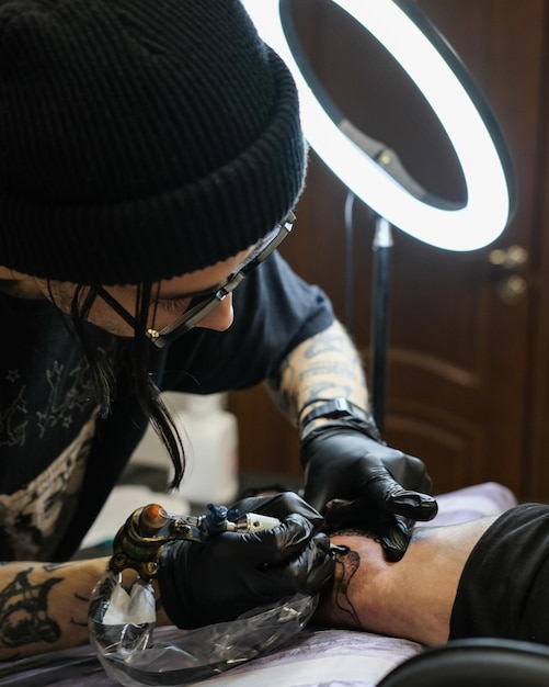 Tatuador profesional mete un tatuaje en la mano del hombre