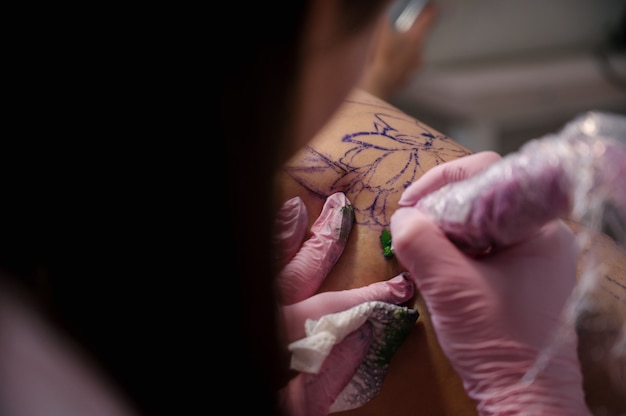 Tatuador profissional faz tatuagem incrível no quadril para mulher jovem e sexy