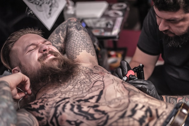 Tatuador profissional faz tatuagem legal no estúdio de tatuagem