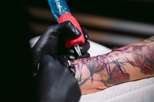 Tatuador profissional faz uma tatuagem na mão de uma jovem garota.