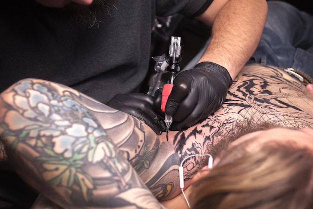 Tatuador profissional faz uma tatuagem no salão do cliente