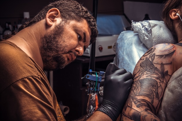 Tatuador profissional fazendo tatuagem no estúdio de tatuagem.