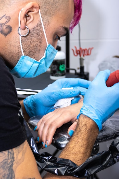 Tatuador profissional fazendo uma tatuagem na mão Fechar o tatuador masculino fazendo uma tatuagem na mão para o cliente