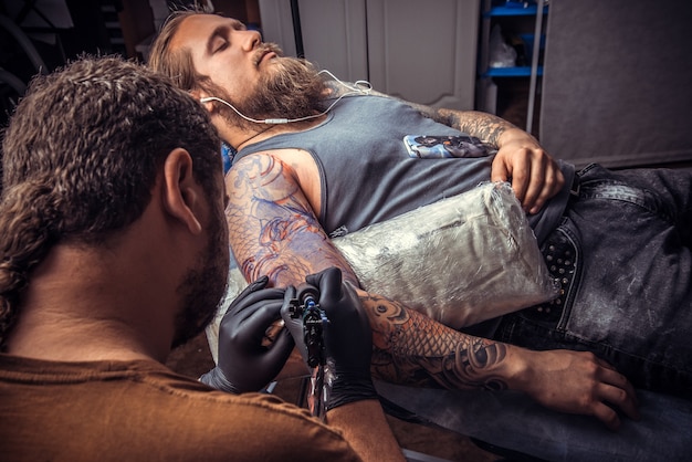 Tatuador profissional mostrando o processo de fazer uma tatuagem no estúdio de tatuagem. / Tatuador profissional no trabalho no estúdio de tatuagem.