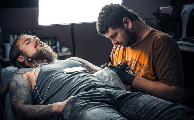 Tatuador profissional no trabalho no estúdio de tatuagem./Tatuador profissional faz tatuagem no estúdio de tatuagem.