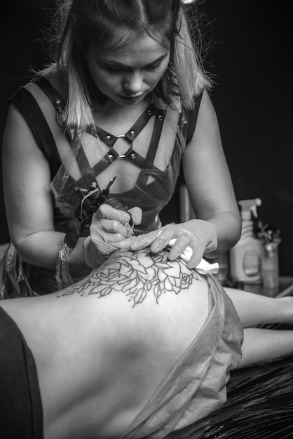 Tatuador profissional trabalha em estúdio de tatuagem./Tatuador profissional trabalhando tatuando em salão.