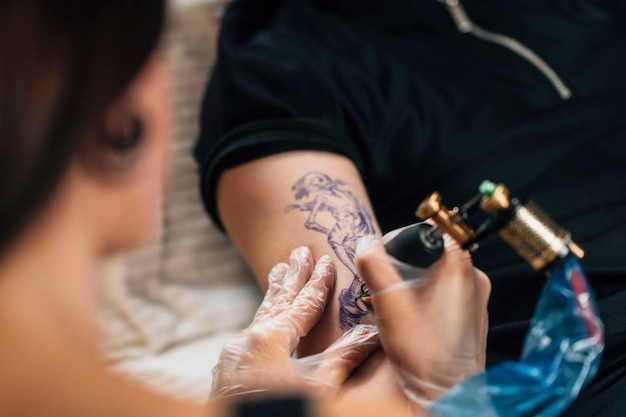Foto tatuador tatuando o braço do homem no estúdio