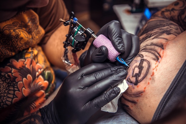 Tatuador en el trabajo en el estudio./Tatuador profesional haciendo tatuajes en el salón de tatuajes.
