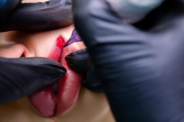 Tatuagem labial em uma máquina de escrever com pigmentos vermelhos o mestre faz os lábios do modelo