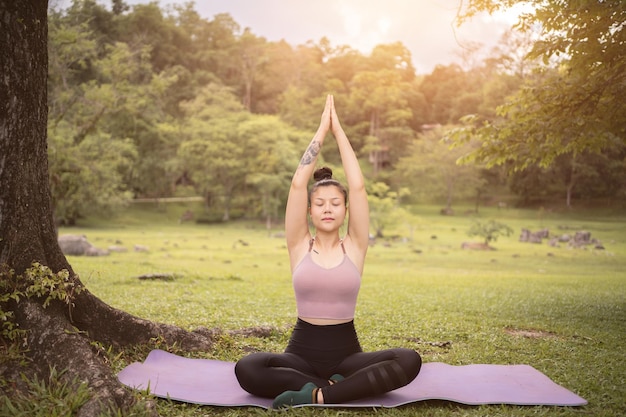 Tatuaje asiático joven haciendo yoga en el parque