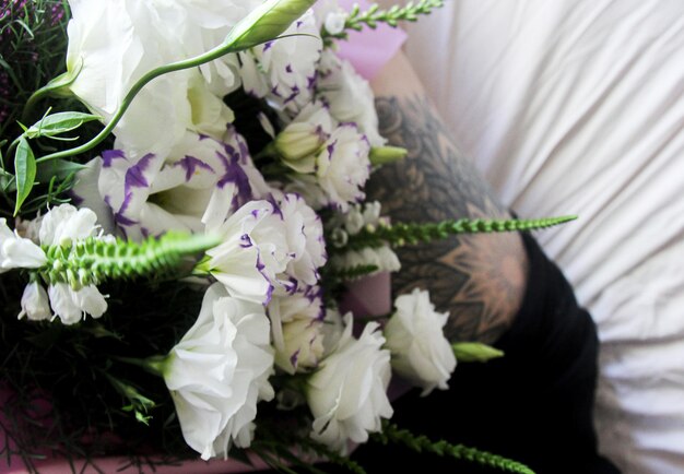 Tatuaje en la pierna, ramo de flores blancas en una sábana blanca