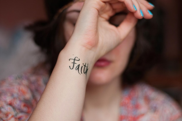 Tatuaje de texto de fe en primer plano en la muñeca de una mujer