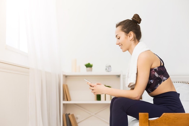 Tausendjähriges Mädchen, das sich nach dem Üben von Yoga am Telefon ausruht