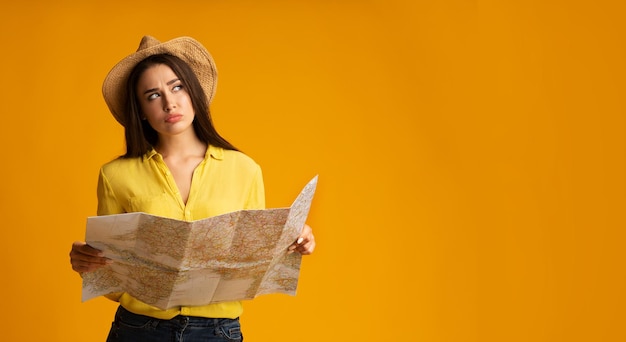 Tausendjähriges Mädchen posiert mit Reisekarte vor gelbem Hintergrund
