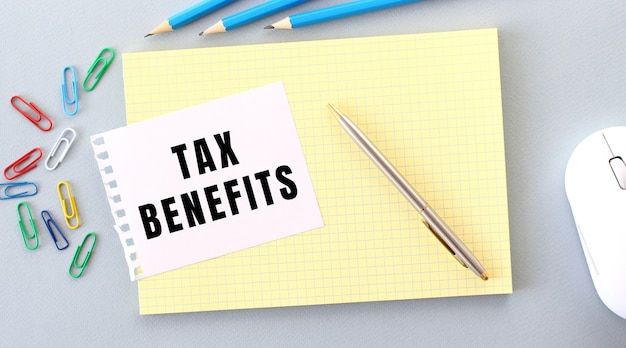 Tax benefits é escrito em um pedaço de papel que fica em um caderno ao lado de materiais de escritório. conceito de negócios.