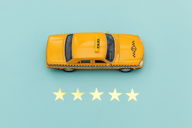 Táxi de carro de brinquedo amarelo e classificação de 5 estrelas isolada em fundo azul.