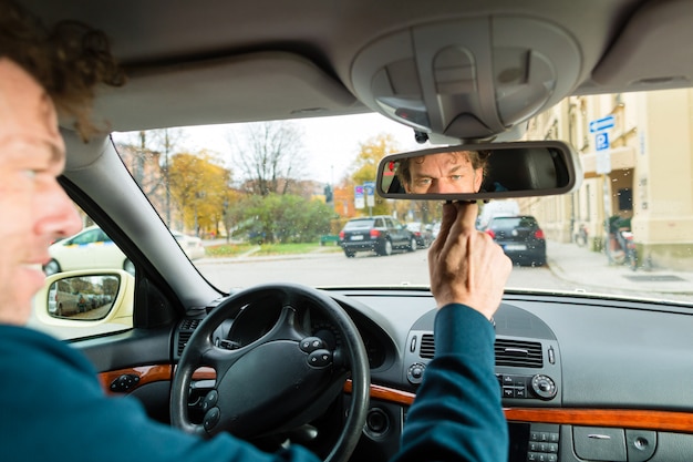 Taxista está mirando en el espejo de conducción