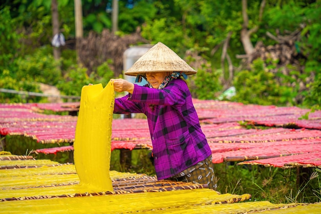 Tay Ninh VIETNAM JUL 06 2023 Fokus Frau aus einem traditionellen Dorf, die farbenfrohe Marmelade zubereitet Sie trockneten frisches Marmelade auf einem Holzgitter für den Markt Lifestyle-Konzept