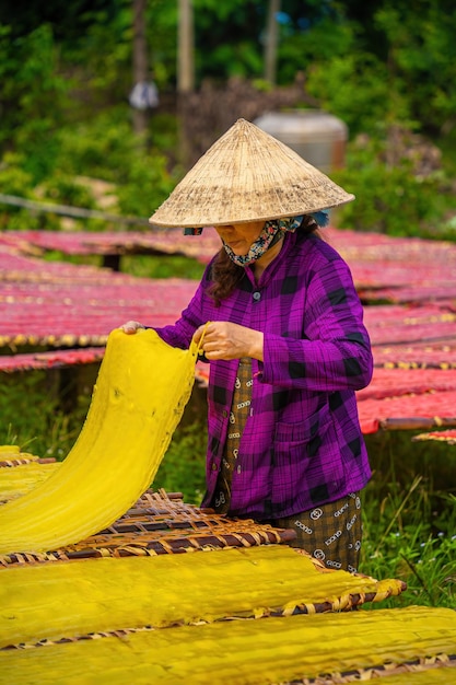 Tay Ninh VIETNAM JUL 06 2023 Fokus Frau aus einem traditionellen Dorf, die farbenfrohe Marmelade zubereitet Sie trockneten frisches Marmelade auf einem Holzgitter für den Markt Lifestyle-Konzept