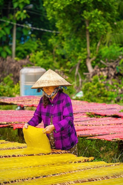 Tay Ninh VIETNAM JULIO 06 2023 Foco mulher de aldeia tradicional fazendo comida de geleia colorida Eles estavam secando geleia fresca em uma grade de madeira para o mercado conceito de estilo de vida
