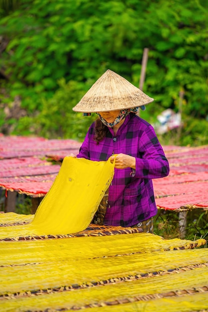 Tay Ninh VIETNAM JULIO 06 2023 Foco mulher de aldeia tradicional fazendo comida de geleia colorida Eles estavam secando geleia fresca em uma grade de madeira para o mercado conceito de estilo de vida