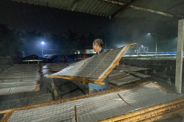 Tay Ninh VIETNAM JULO 07 2023 Foco homem da aldeia tradicional fazendo comida de macarrão Eles estavam secando macarrão fresco em uma grade de madeira para o mercado conceito de estilo de vida