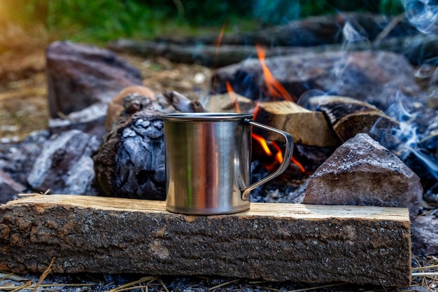 Taza de acero en un fuego abierto en la naturaleza Cocinar en llamas Camping en verano