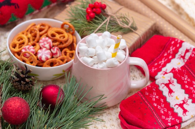 Una taza con adornos navideños y de año nuevo de malvavisco en un plaid tejido