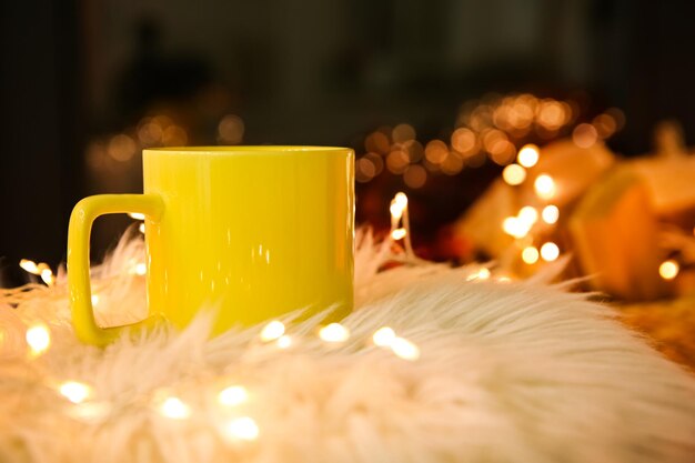 Taza amarilla con bebida caliente y luces de hadas en piel sintética.