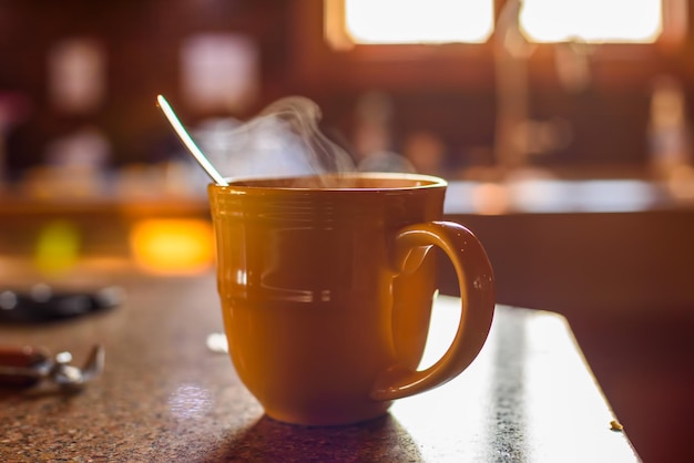 Foto una taza amarilla de café caliente con vapor saliendo de la parte superior.