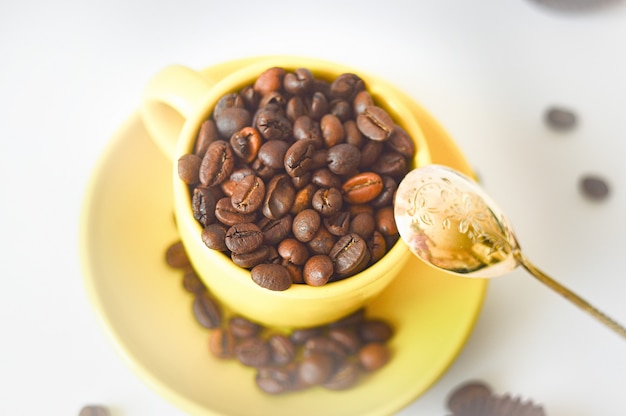 Taza amarilla llena de granos de café natural