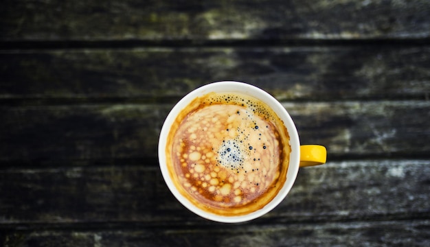 Una taza amarilla de sabroso café sobre fondo de mesa de madera rústica