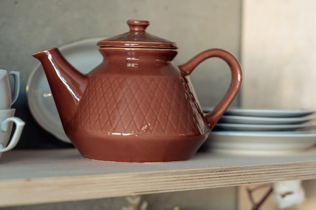 Taza de arcilla marrón en un estante blanco con tazas y platos