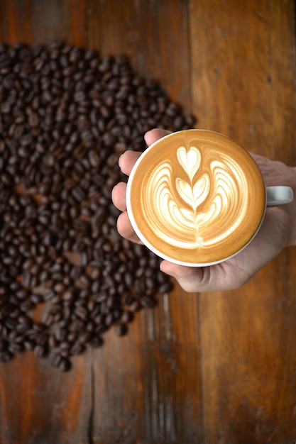 taza de arte del latte del café que hace por el barista en viejo fondo de madera.