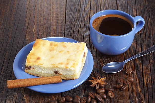 Taza azul de café caliente con tarta de queso en la mesa de madera antigua